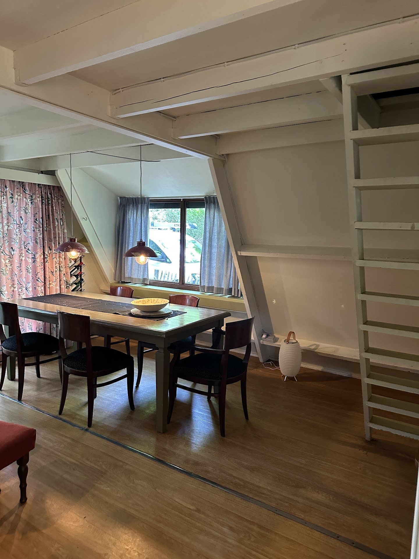 Binnenruimte met eettafel, boekenkast en zichtbare plafondbalken