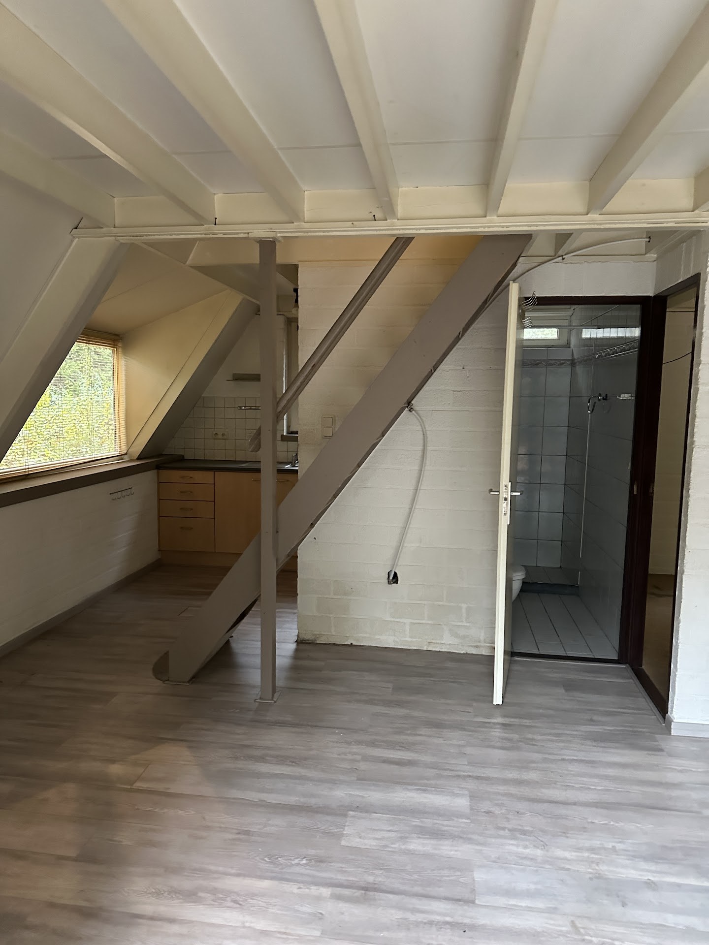 Lege binnenruimte met schuin dak, trap en doorgang