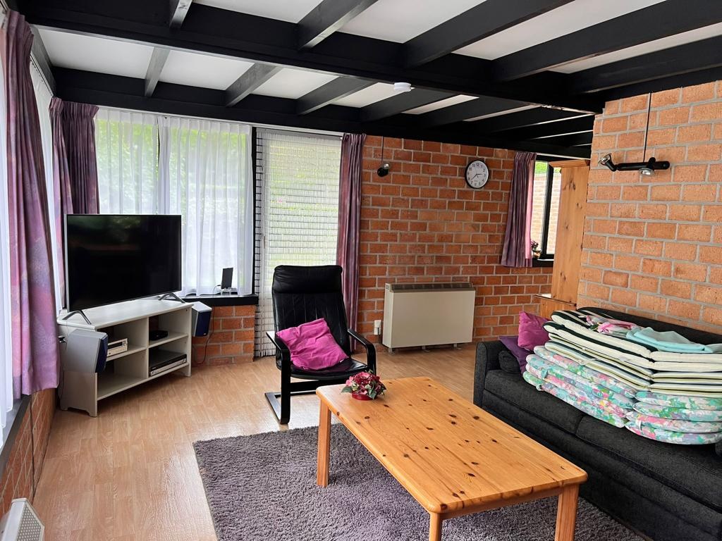 Interieur met zichtbare bakstenen wand, donkere balken en zitmeubels